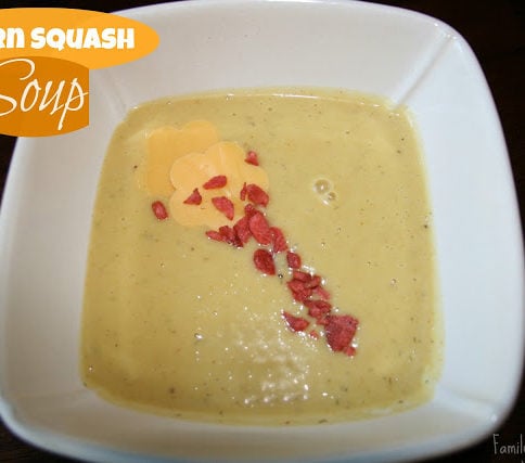 Acorn Squash Soup in a white bowl and topped with bacon crumbles and cheese flowers