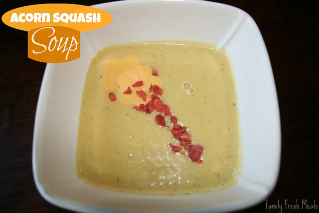 Acorn Squash Soup in a white bowl and topped with bacon crumbles and cheese flowers