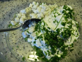 Mixing together creamy stuffing mixture in a glass bowl with a spoon stirring