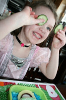 small girl holding up slices of cucumbers, smiling