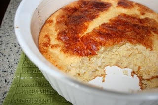 Cooked Puffed Cheddar Rice Casserole in white casserole dish with a scoop out of it