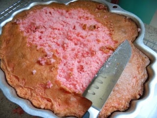 large knife cutting off extra cake from top of pan