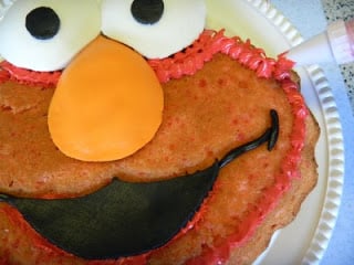 frosting the outer edges of elmo cake with piping bag and red frosting