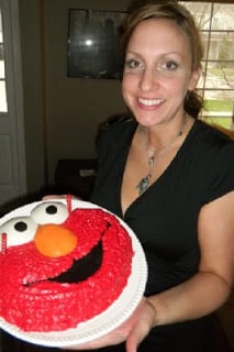 Woman in a black dress holding elmo cake 