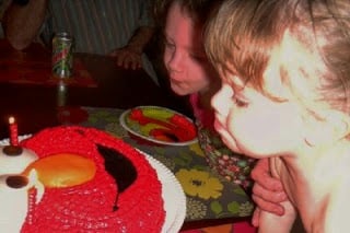 children blowing out candles on Elmo cake