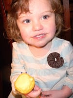 child holding a yellow cake pop