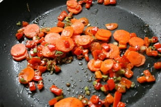 scallion whites, bell peppers and carrots cooking in a frying pan