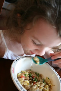 child sitting at a table eating the fried rice pilaf