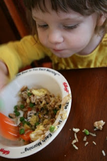 child sitting at a table eating the fried rice pilaf