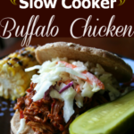 Side photo of the Slow Cooker Buffalo Chicken served on a bun and topped with cole slaw. On the side is a pickle and corn on the cob