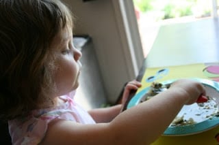 child sitting at a table , scooping soup with a spoon