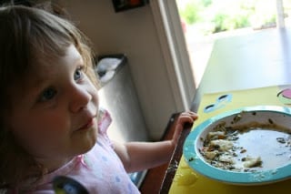 child sitting at a table with bowl of soup in front of her