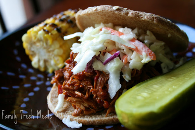 Slow Cooker Buffalo Chicken Sandwiches served on a bun and topped with coleslaw with a large pickle on the side