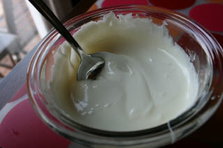 Melted White chocolate Chips in a small glass dish, with a spoon stirring