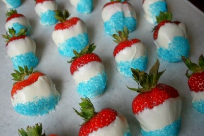 Red, White & Blue Chocolate Covered Strawberries lined up on a sheet of parchment paper