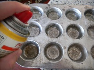 spraying mini muffin tin with cooking spay