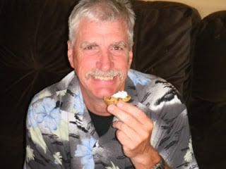 a man holding a Chocolate Chip Cookie Cups with Almond Buttercream Frosting, smiling.