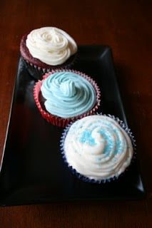 three frosted cupcakes sitting on a rectangle plate