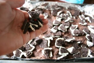 broken oreos being placed on top of pressed in batter