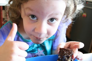 child giving a thumbs up while eating cake bar