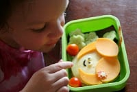 child sitting at a table looking at the lunchbox