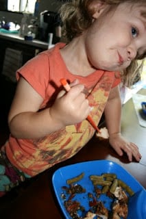 small child eating Thai Garlic & Basil Chicken with chopsticks