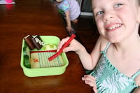 child sitting a table with back to school lunchbox, holding a piece of licorice 