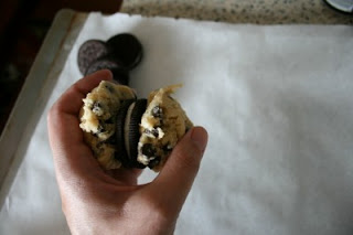 a hand holding oreo cookie surrounded by chocolate chip cookie dough