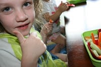 2 children sitting at a table with lunchbox