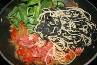 sauted leeks, tomatoes, pasta and fresh spinach in a pan