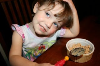 child sitting a table with a bowl of chicken salad appetizer