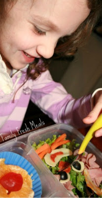 a child sitting at a table, eating the clowning around lunchbox