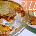 Baking dish of pizza dip with scoop of dip taken out