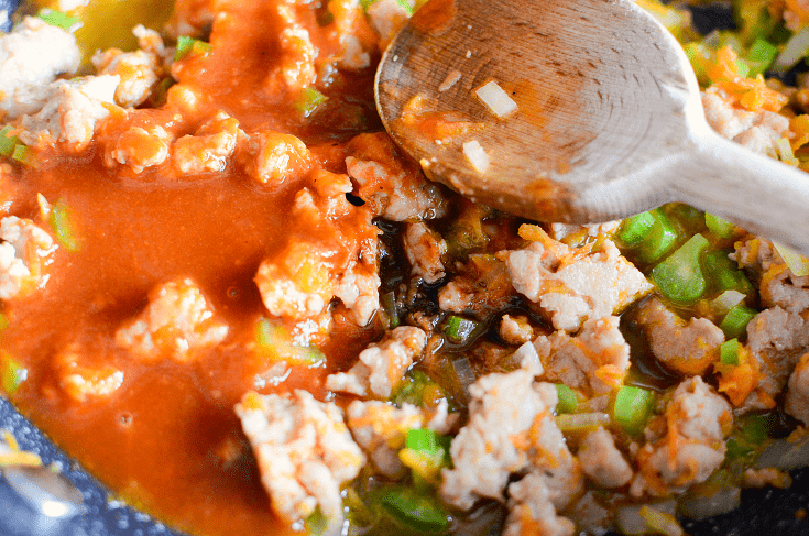 mixing sauce into pan with vegetable turkey mixture with a wooden spoon