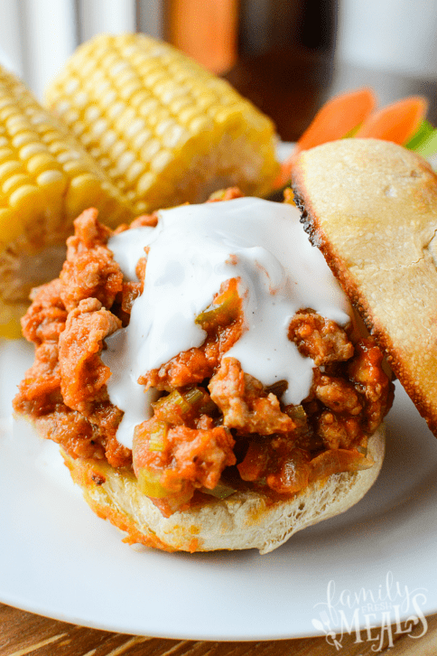 Buffalo Sloppy Joes served on a toasted bun, with corn on the cob on a white plate