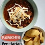 top down photo of Darryl's Famous Vegetarian Chili, topped with shredded cheese and a side of corn chips