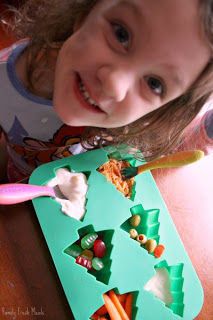 child sitting at a table with Muffin Tin Meal Olive My Christmas Tree