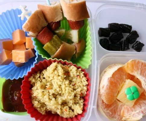 Top down picture of Hot Dog Kabob lunch box - hot dog kabobs, couscous, cheese cubes, orange slices and fruit snacks