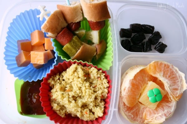 Top down picture of Hot Dog Kabob lunch box - hot dog kabobs, couscous, cheese cubes, orange slices and fruit snacks