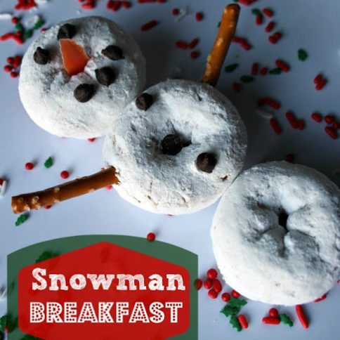 Snowman made of powdered mini donuts, pretzels and mini chocolate chips, on a white plate, surrounded by holiday food sprinkles