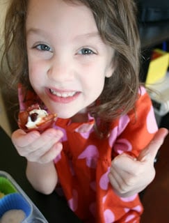 Small child eating a Prosciutto Cups with Cheese & Herb Filling and giving a thumbs up