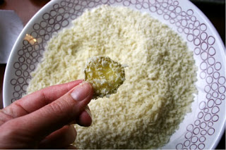 Pickle slice being dipped in bread crumbs 