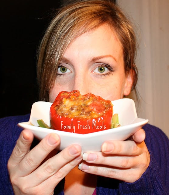 Woman holding a cooked stuffed pepper on a white plate