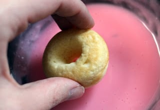 Dipping mini donuts into pink frosting