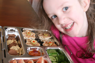 child sitting at a table smiling with planet box lunch box