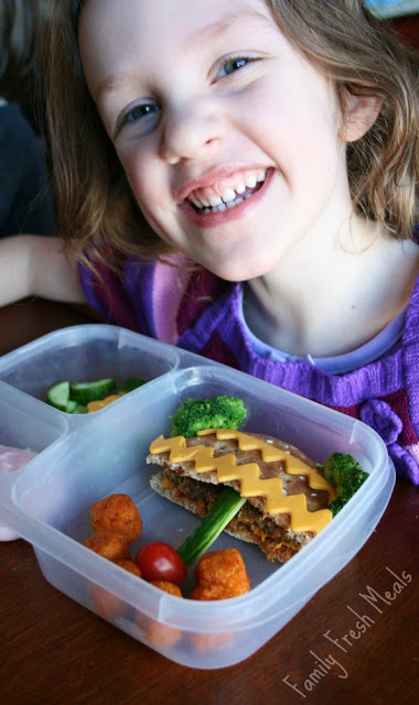 Child smiling, sitting at a table with Potted Plant Lunchbox