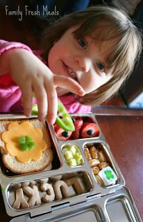 Child sitting at a table with lucky lunch box