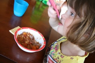 small child sitting at a table eating Crockpot Irish Stew