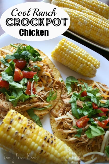 2 Chicken Tostadas on a white plate with corn on the cob