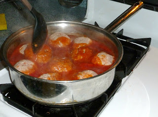 meatballs simmering in a cooking pan with sauce